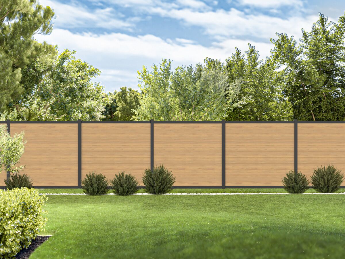 Wooden privacy fence with green grass and trees in the background