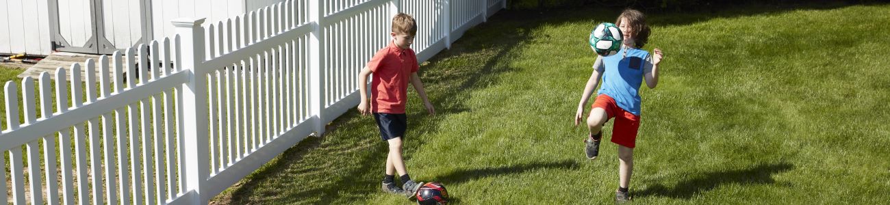 Kids playing soccer by an ActiveYards fence